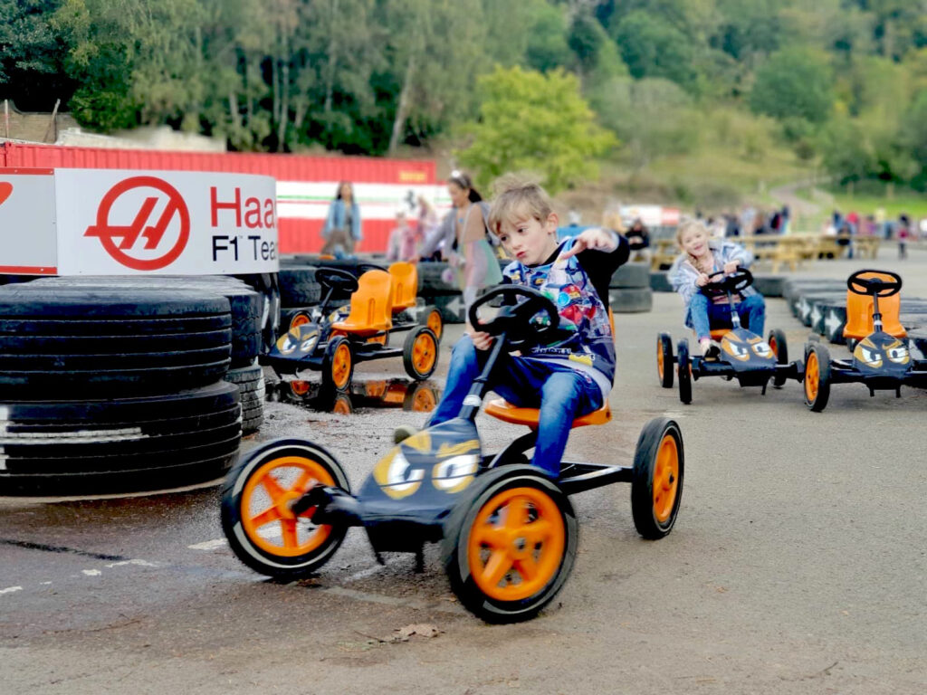 Children racing colourful pedal go-karts around the outdoor karting track